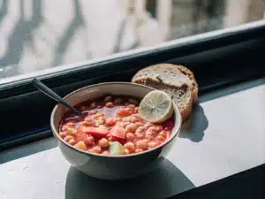 Leblebi-Suppe mit weichen Kichererbsen in einer Schale, dazu Brot und Limette