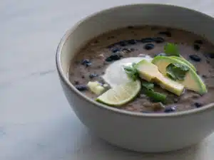 Sämige schwarze Bohnensuppe mit Avocado, saurer Sahne, Koriander und Limette