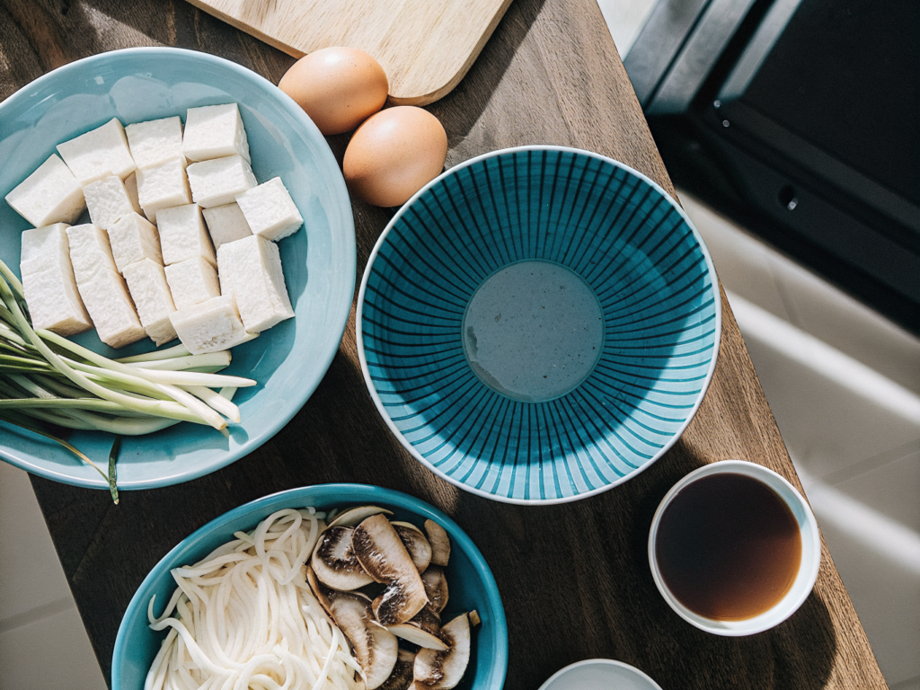 Zutaten für eine pikante Suppe mit Tofu, Pilzen, Schweinefleisch und Hühnerbrühe