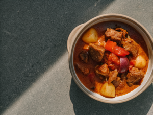 Gulasch mit Paprika und Zwiebeln in einer Schale, dazu Salzkartoffeln