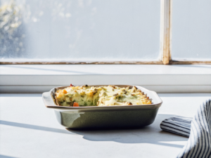 Kartoffelauflauf mit Möhren, Kohlrabi und Erbsen unter goldbraunem Käse