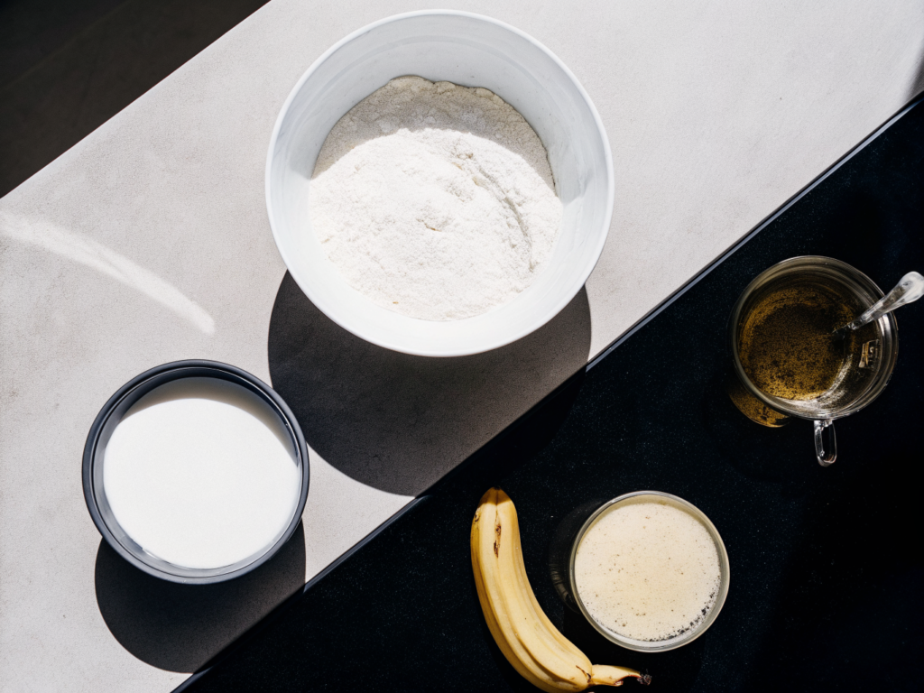 Vegane Vollkornwaffeln mit Apfel-Bananenmus 2 Waffelteig und Zutaten wie Vollkornmehl, Haferdrink und Obstmus auf einer Arbeitsfläche