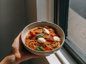 Vollkornspaghetti mit Kirschtomaten, Mozzarella und frischem Basilikum in einer Schale