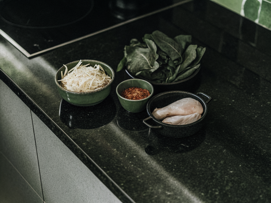 Mais-Tortillas, Hähnchenbrust, Enchiladasauce und geriebener Käse auf einer Arbeitsfläche