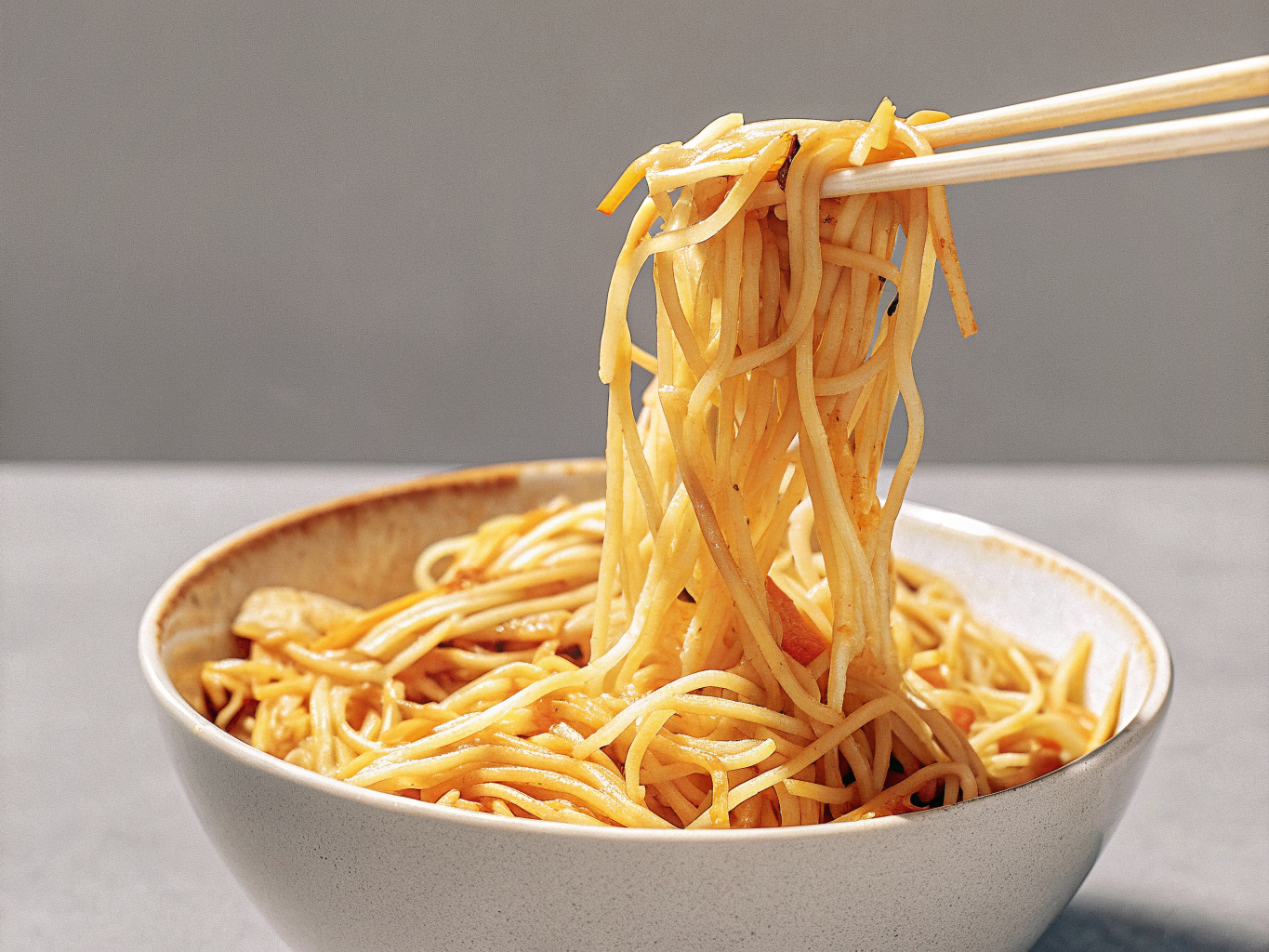 Gebratene Nudeln aus dem Wok mit Hähnchen 1 Gebratene Woknudeln mit Hähnchen, Ei, Karotte, Lauch und Sojasprossen in einer Schale