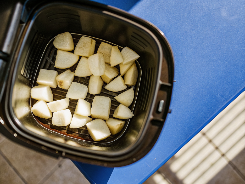 Patatas bravas aus dem Airfryer 2 Kartoffeln und Zutaten für Patatas bravas neben dem Korb eines Airfryers