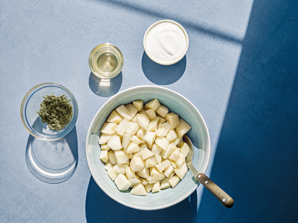 Rohe Kartoffelwürfel und Zutaten für den Kräuter-Kapern-Dip auf der Arbeitsfläche