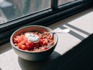 Chili con Carne mit Bohnen, Mais und Paprika, serviert mit einem Klecks Crème fraîche