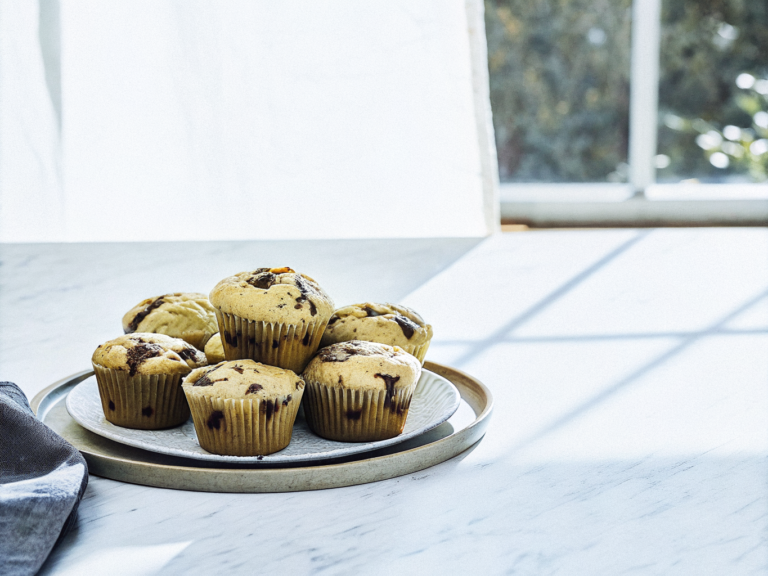Schokomuffins mit Haselnüssen und sichtbaren Schokoladenstücken auf einem Keramikteller