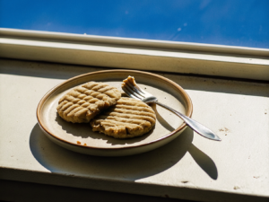 Goldbraune Erdnussbutter-Kekse mit Gabelmuster auf einem schlichten Teller