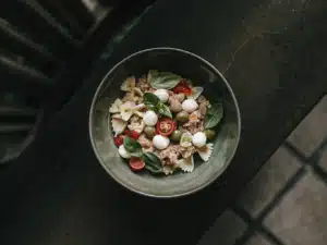 Farfalle-Nudelsalat mit Thunfisch, Mozzarella, Tomaten, Oliven und Basilikum in einer Schüssel