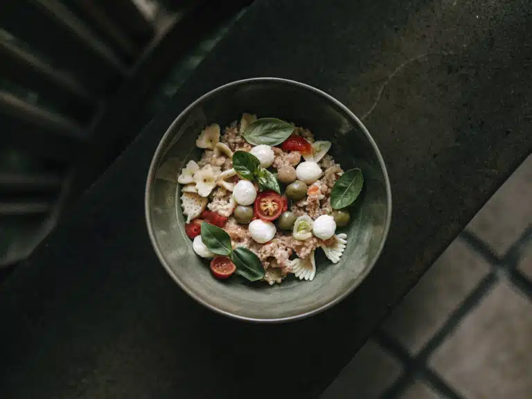 Farfalle-Nudelsalat mit Thunfisch, Mozzarella, Tomaten, Oliven und Basilikum in einer Schüssel