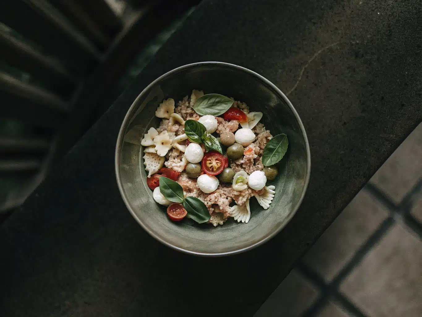 Farfalle-Nudelsalat mit Thunfisch, Mozzarella, Tomaten, Oliven und Basilikum in einer Schüssel