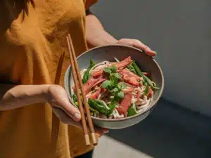 Reisnudelsalat mit Räucherlachs, Zuckerschoten, Frühlingszwiebeln und Koriander in einer Schale