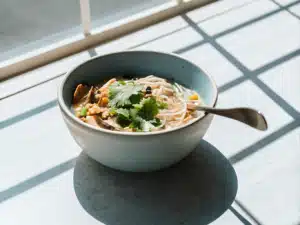 Schale Reisnudelsuppe mit Lachs, Shiitake, Mais und frischem Koriander