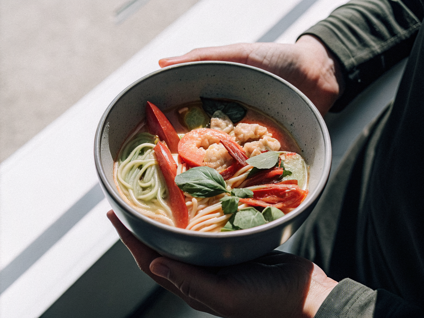 Udon-Nudelsuppe mit Garnelen, Gemüse, Kokosbrühe, Kräutern und roter Chili in einer Schale