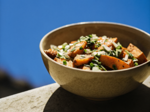 Gerösteter Süßkartoffelsalat mit Frühlingszwiebeln, Schnittlauch und Dressing in einer Schale
